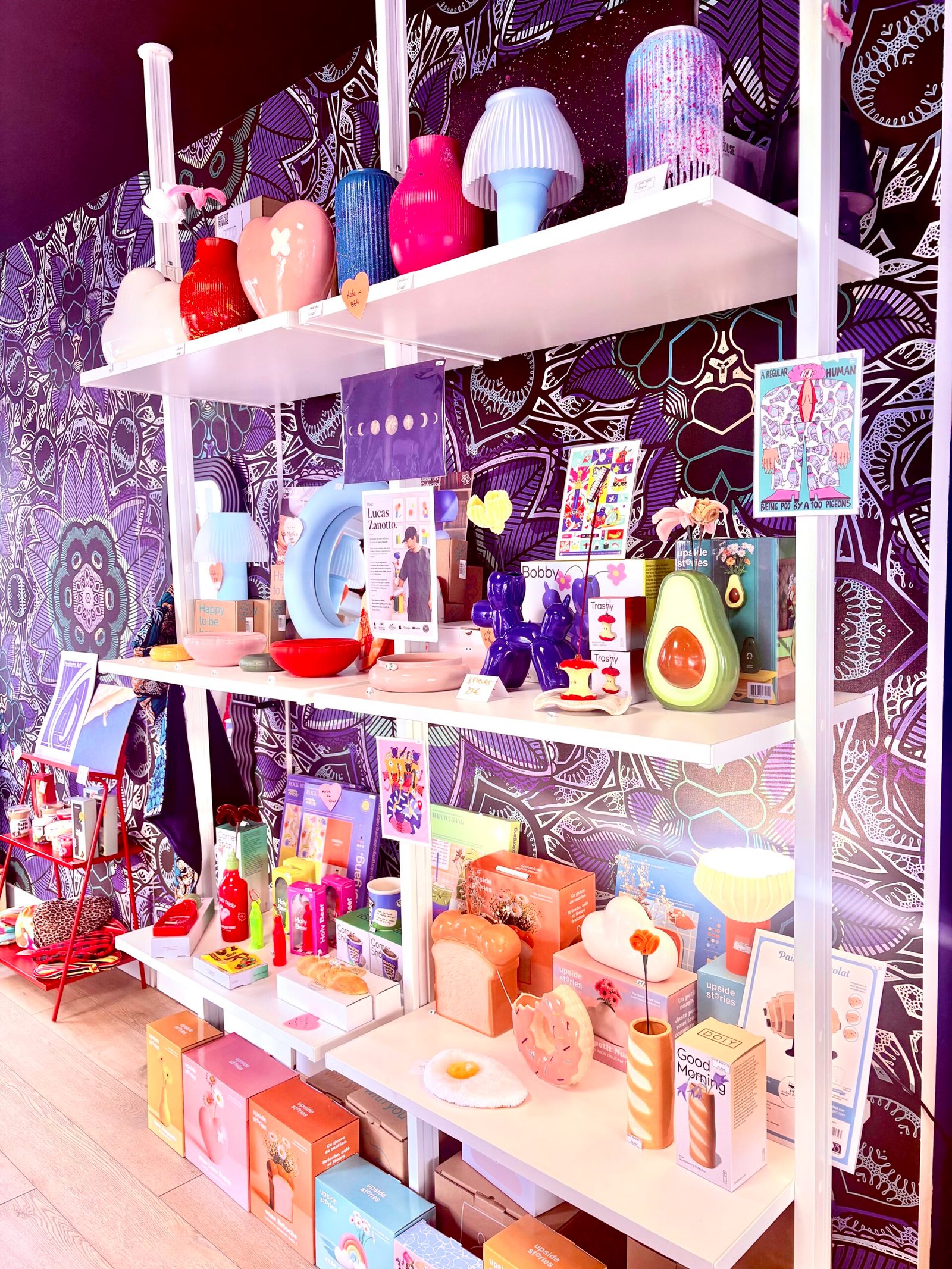 L'œil de MYLO : les étagères de la boutique, objets colorés sur papier peint violet