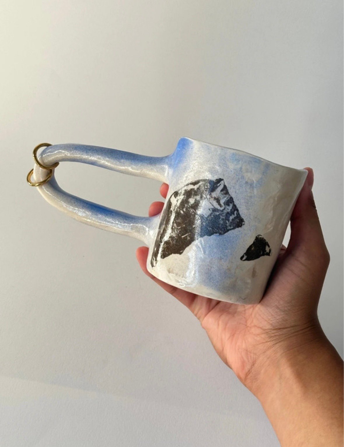 Mug en céramique de Fionaë tenu par l'anse, avec un anneau doré
